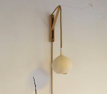 Handgemaakte vilten wandlamp Luminosa in maat S, bevestigd aan een houten houder.