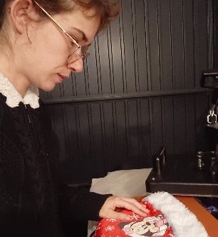 A woman customizes a Christmas Santa hat with a heat press, ideal for holiday gifts and personalized apparel.
