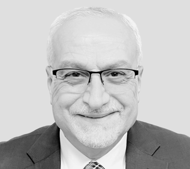 A picture of Dr. Burhan Ghanayem smiling and facing the camera wearing a suit