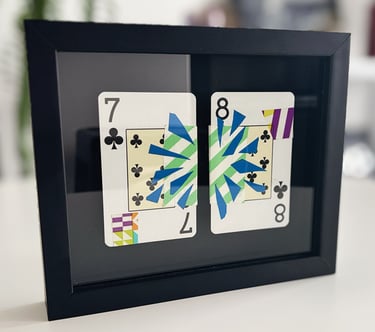 foto da arte contemporânea que é feita de washi tape e fita isloante sobre baralho. A obra está emoldurada em fundo preto.