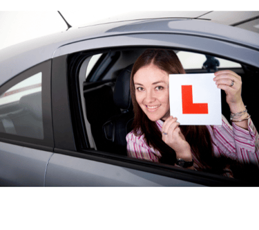 a woman holding up a L red sign for her car. starting her car leaning expirance with let's pass 1st.