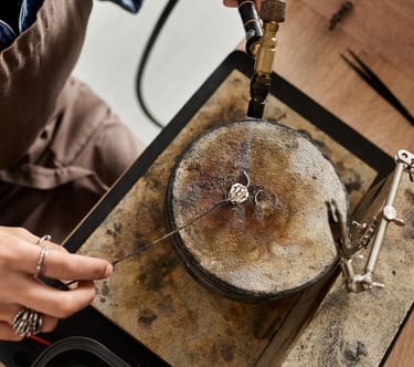 Joyero utilizando un soplete de butano para soldar un anillo de plata sobre un bloque de soldadura.