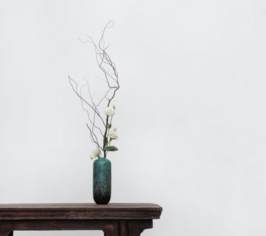 Photo E-commerce d'un vase élégant vert et noir placé sur le bord d'une table en bois avec 3 roses