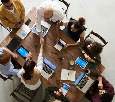 Clients and IT professionals meeting at a table with laptops and tablets, representing managed IT services and support