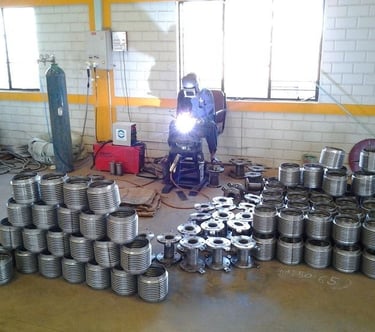 a man welding a metal pipe in a warehouse