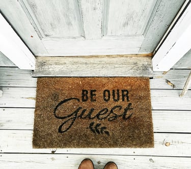 The entrance to the guesthouse with a doormat and the inscription "Be our guest"