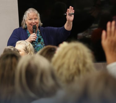 Debbie Chen speaking with a microphone to an engaged audience, Business Leadership Coach and speaker.