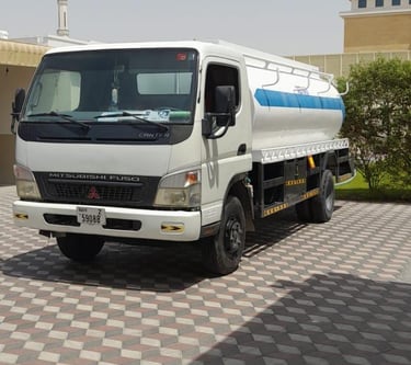 a truck with a tanker truck parked in front of a building