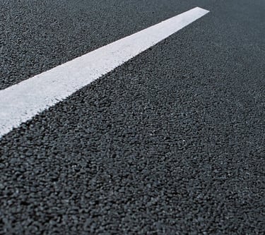 Close-up of a fresh black asphalt road surface with a single white painted traffic line.