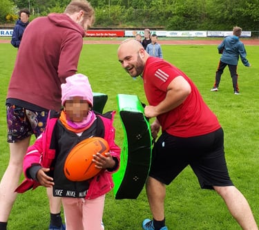 a man and a little girl learning the basics of rugby