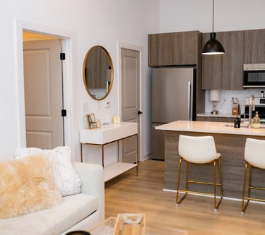 Modern open concept kitchen and living room featuring wood cabinets, quartz island, and gold accents.
