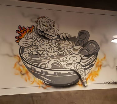 Anime image of a monster in a bowl of ramen painted on the wall of a restaurant.