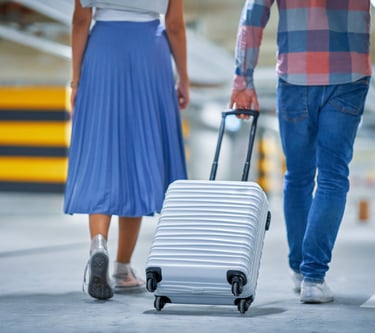 Stylish couple wheeling luggage through the airport — Ready to chase Disney magic