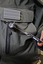 A retractable fishing gear zinger attached to a waterproof fly fishing wading jacket pocket.