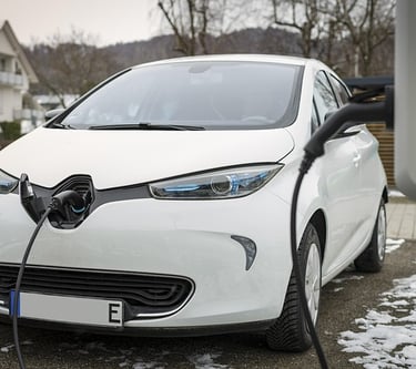 Un automóvil eléctrico Renault Zoe blanco conectado a una estación de carga doméstica en una entrada