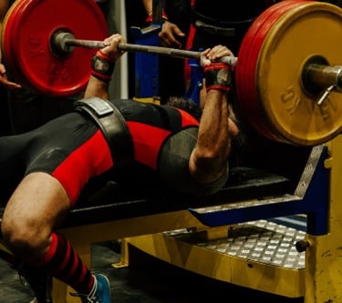 Professional powerlifter performing a heavy bench press with weighted plates during a competition.