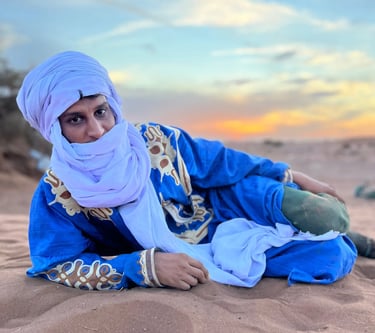 Hssein Liaichi, wearing traditional nomad dress, lying in the desert on a Moroccan camel trek