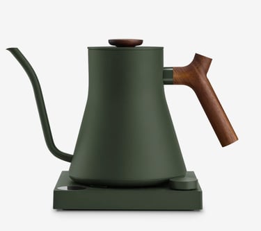 Matte green electric gooseneck kettle with walnut wood handle on a heating base.