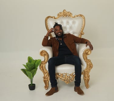 Chevon sitting in a chair with a plant in front of him