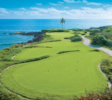A lush oceanfront golf course at a Sandals luxury resort with green fairways overlooking the blue sea.