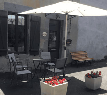 Entrée du gîte avec la table, les chaises sous un parasol