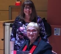 a woman sitting at a table with a book signing