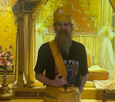 a man at Istana Maimun in traditional Indonesian ceremonial hat and sarong with a kris