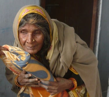 an old woman in a yellow shawl holding a blanket