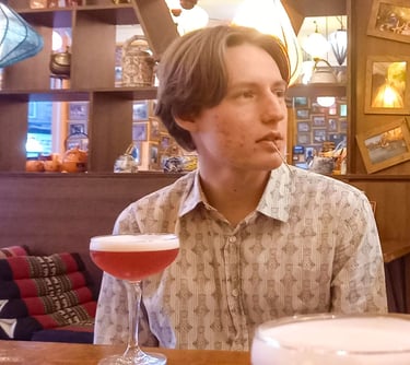 Portrait shot of Byron sitting in a trendy restaurant with a drink.