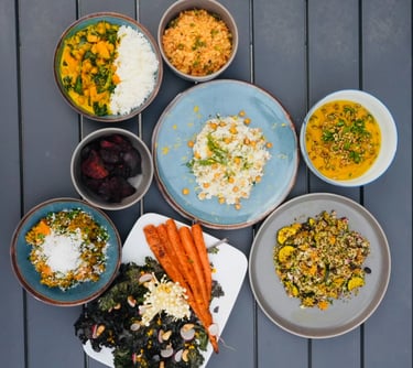 a table with bowls of vegetarian plant-based food and a bowl of vegetables carrots chickpeas