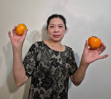 a woman holding two persimmons in her hands