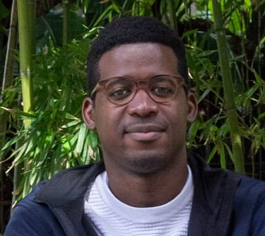 man  with glasses sitting in front of bamboo 