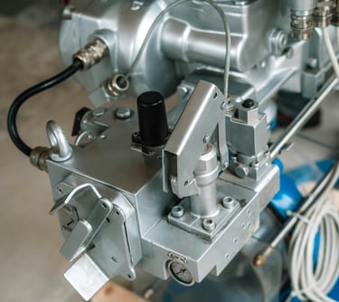 Close-up of a high-pressure industrial sprayer machine with metal valves and silver hardware components.