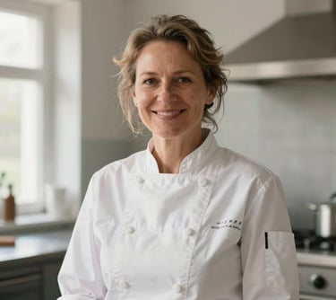 A warm portrait of a middle-aged woman with a kind smile, wearing a professional chef jacket in a clean, modern kitchen in Berlin. Soft morning light, focusing on her friendly face. Central European setting.