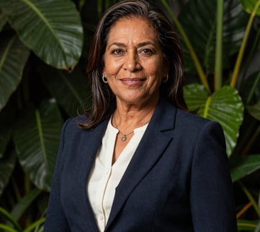 A professional portrait of a South American woman in her 50s, representing Elsa Antonelli. She is dressed in elegant but practical attire, standing in front of a backdrop of lush green foliage. Her expression is warm and professional, embodying the brand's heritage.