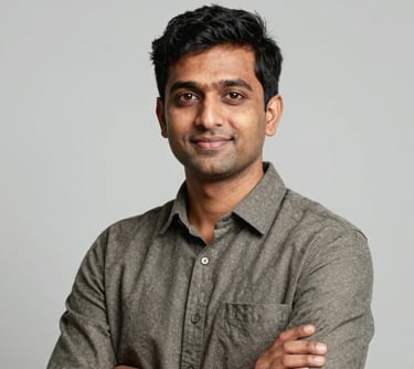 A professional portrait of a tech expert in business casual attire in a South Asian / Global setting, looking confident and approachable, set against a clean, light grey studio background.
