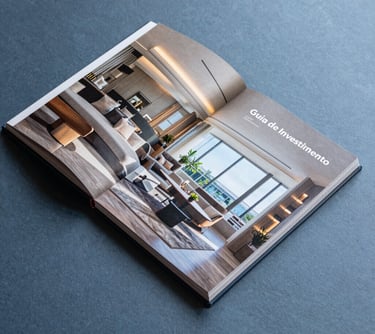A high-end photography book or brochure lying on a slate blue surface, titled 'Guia de Investimento', showing interior design details of a luxury Brazilian penthouse.