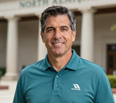 Professional portrait of a middle-aged sports executive in a teal polo shirt with a North American / Mexican architectural background. The lighting is soft and natural, conveying leadership and approachability.