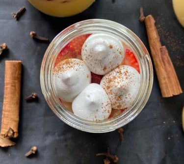 Dessert jar plated with meringue dots, strawberries and cinnamon as background