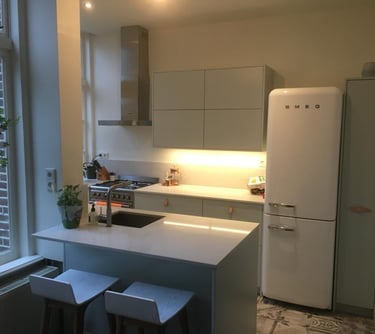 a kitchen with a refrigerator, refrigerator, and stool