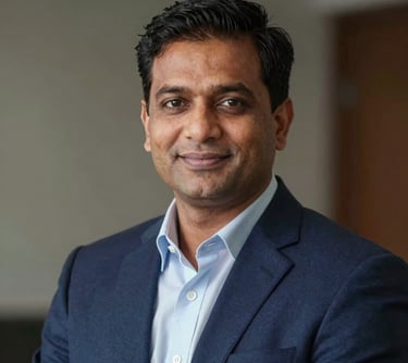 A professional corporate headshot of a South Asian male real estate expert in his 40s, sharp navy blazer, confident and trustworthy expression, premium lighting.
