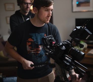 Film studio camera operator standing in front of a camera and holding another camera