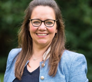 Woman wearing glasses and a blue jacket at a film production company