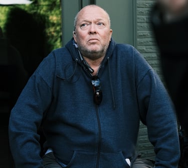 Director of Photography (DP) at a film studio, man seated on a bench in a park