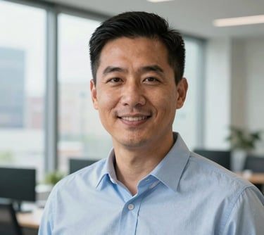 A professional headshot of a male operations director in a North American business setting. He has a friendly but authoritative expression, wearing a light blue shirt. The background features modern office windows with a glimpse of a clean, urban environment.