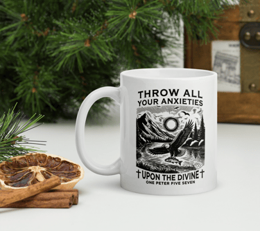 White ceramic coffee mug with a religious graphic featuring an eagle and mountain landscape next to cinnamon sticks.