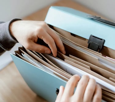 Person organizing documents in a light blue expanding accordion file folder for office storage.