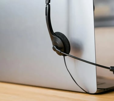 Professional call center headset with microphone resting on a silver laptop for remote work.