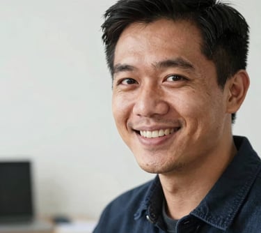 A professional portrait of a creative male designer in his late 20s, focused and smiling, in a bright studio environment. Southeast Asian / Indonesian context, high quality headshot.
