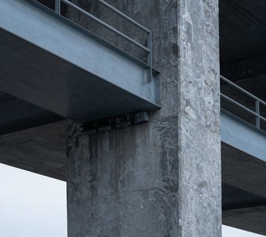 Tight macro-detail of a modern steel and concrete structural pillar, high-contrast architectural lighting, cool slate grey tones, sharp focus, 35mm